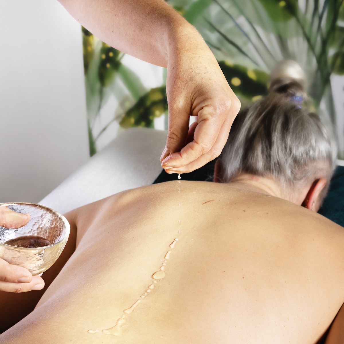 Massage : on voit une femme allongée dos nu, et Adèle Meunier qui lui verse de l'huile sur le dos